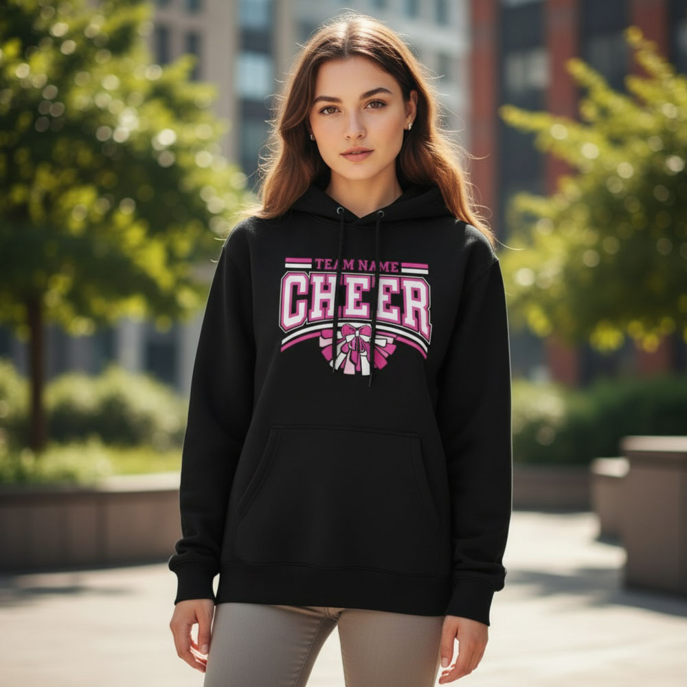 Female model wearing a black custom Pink Out cheer Hoodie with a personalized team name for breast cancer awareness fundraising.